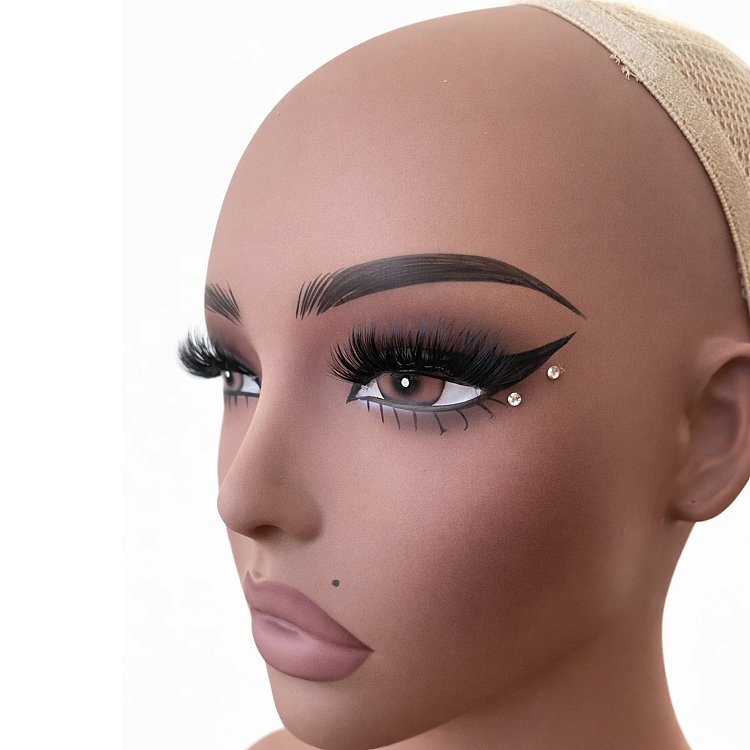 Nahaufnahme der Seitenansicht des Christian Artesio Mannequin-Kopfes in Tan mit auffälligem Augen-Make-up und Perückennetz.