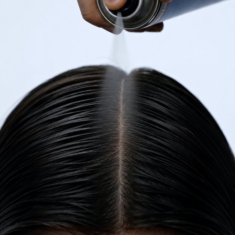 Close-up of Christian Artesio Dry Shampoo being sprayed onto the hair roots during application.